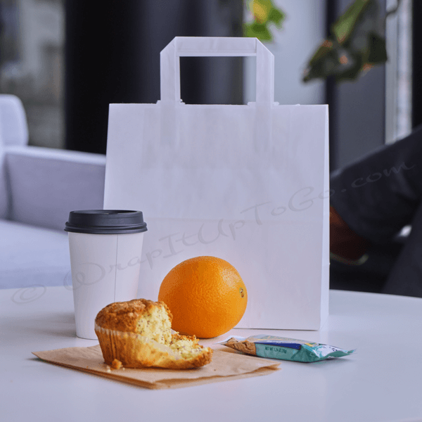 Coffee, orange, muffin, and paper bag on table.